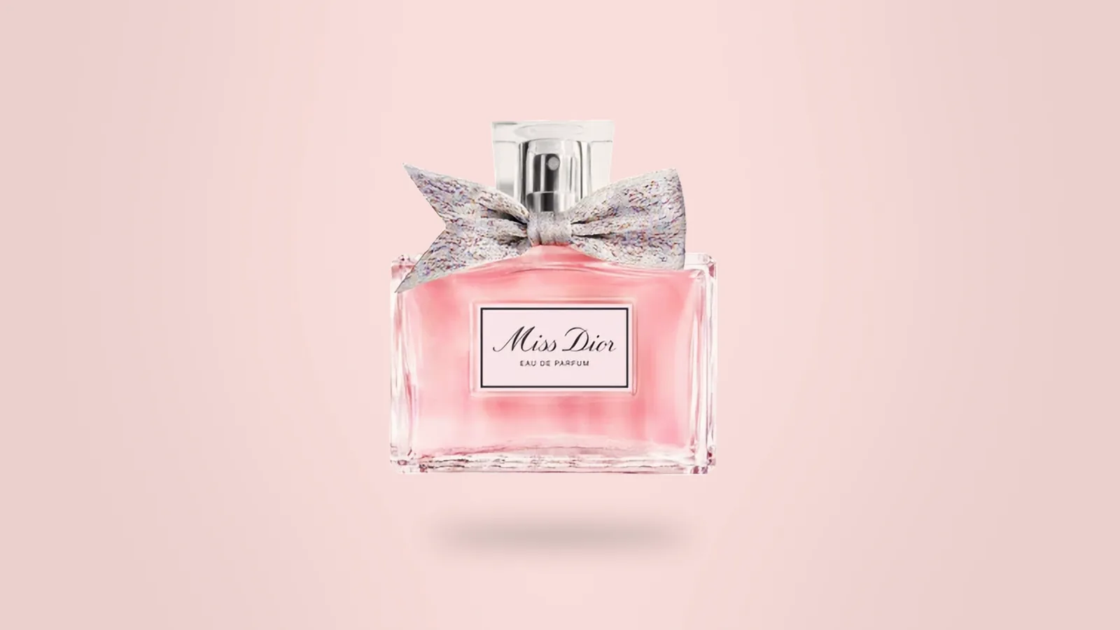 Our photo of a Miss Dior Eau de Parfum bottle with its grey bow on a soft pink backdrop