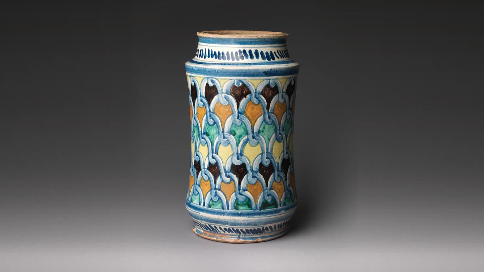 A maiolica storage jar (albarello) of about 1500, painted with interlaced blue loops over scales of green, ochre, yellow and dark brown, from The Met's open collection