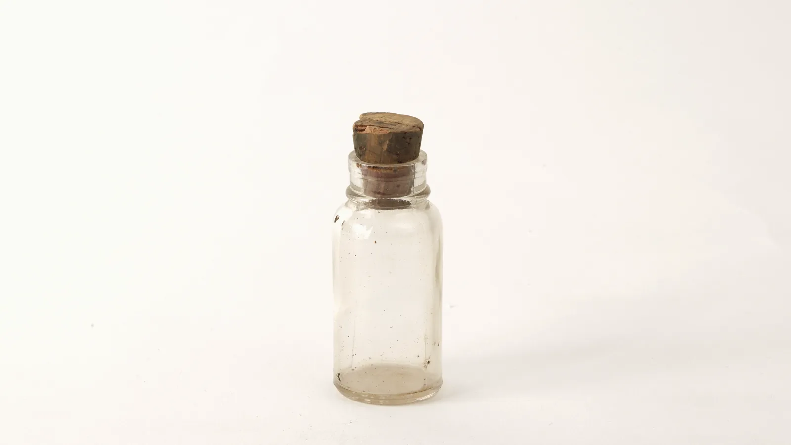 A small clear glass vial closed with a cork, the kind used for perfume raw materials